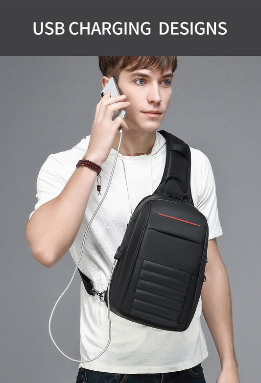 Person wearing a black crossbody bag with USB charging port, holding a phone, on a gray background.