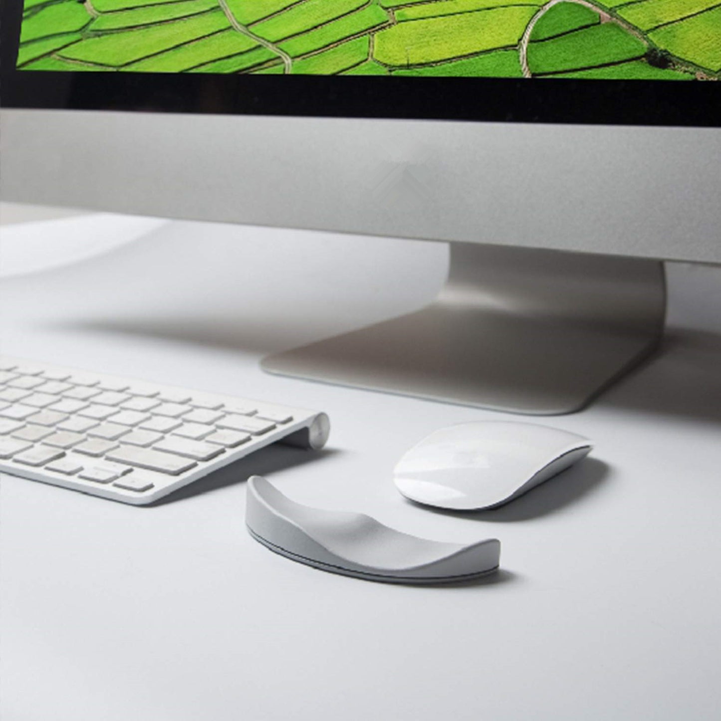 Computer monitor with keyboard, mouse, and wrist rest on a desk