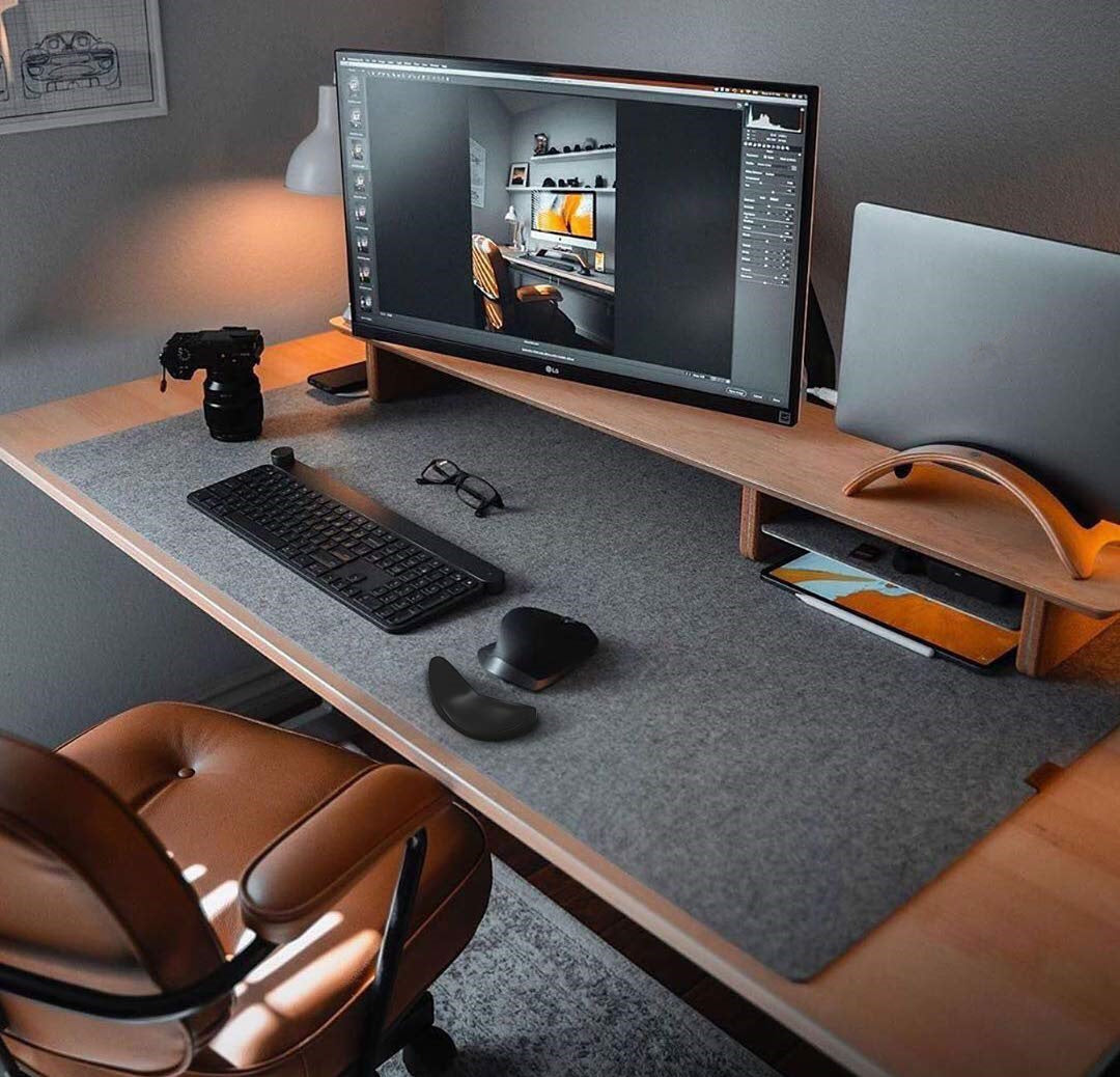 Modern office desk setup with computer monitor, keyboard, mouse, and camera.