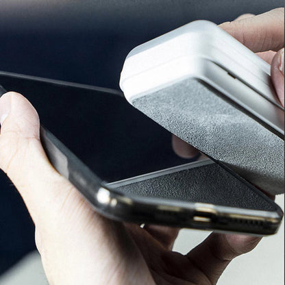 Person cleaning a smartphone screen with a white cleaning tool