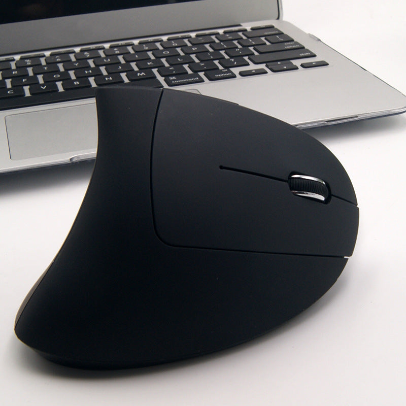Black ergonomic mouse in front of a laptop on a white surface