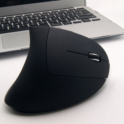 Black ergonomic mouse in front of a laptop on a white surface