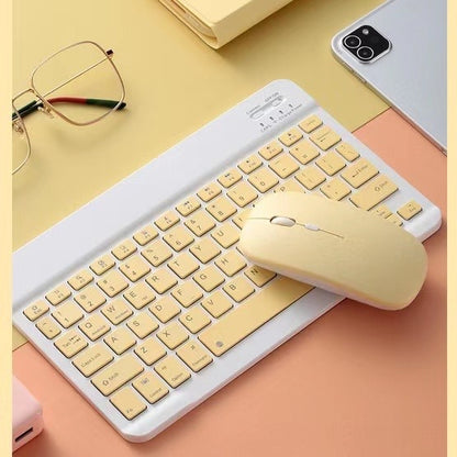 Beige keyboard and mouse set on a yellow surface with glasses and phone.