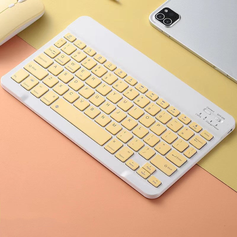 Yellow keyboard on a colorful surface with a phone and mouse in the background