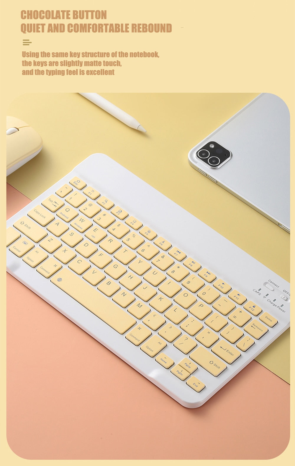 Yellow keyboard on a pink surface with a phone and mouse in the background