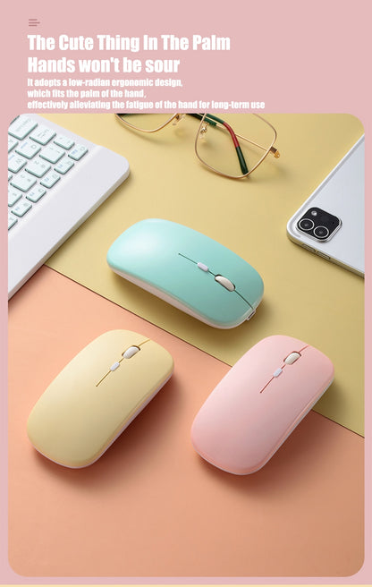 Three colorful wireless mice on a desk with a keyboard, phone, and glasses.