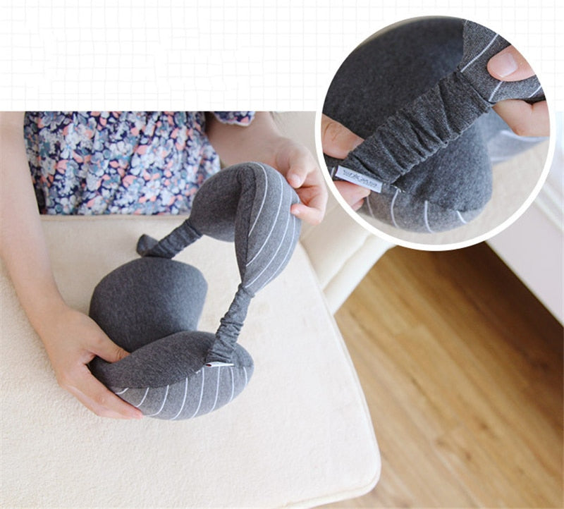 Gray neck pillow with striped pattern held by a person, close-up of brand label.