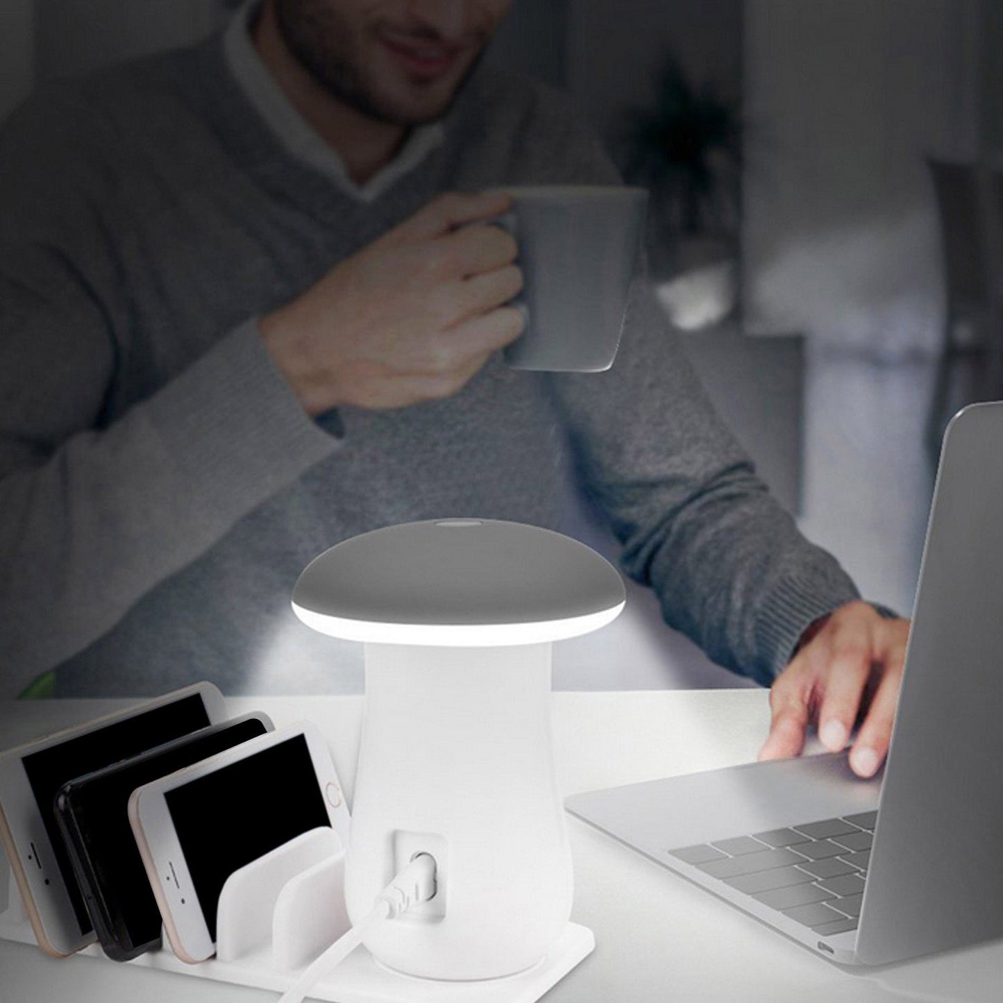 Person using a laptop with a small lamp and phone charger on a desk