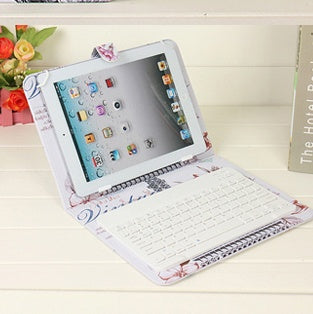 Tablet with keyboard cover on a white surface, surrounded by decorative items.