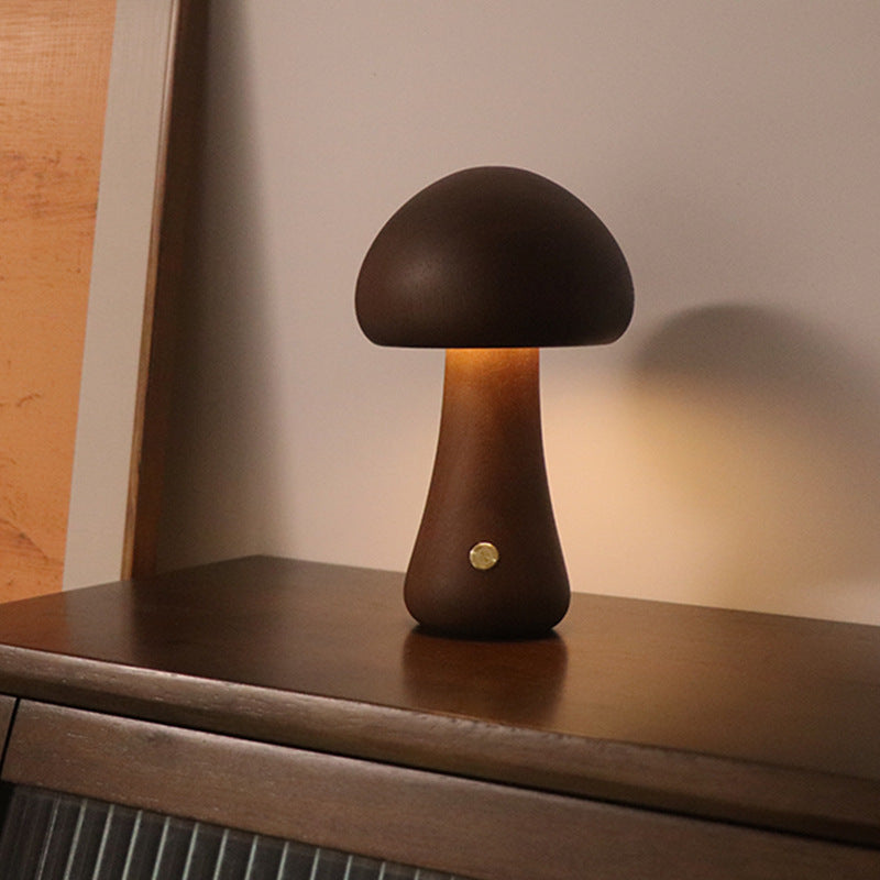 Mushroom-shaped table lamp on a wooden surface with a warm glow.