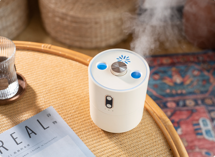 White humidifier on a wooden table with a magazine and glass in the background