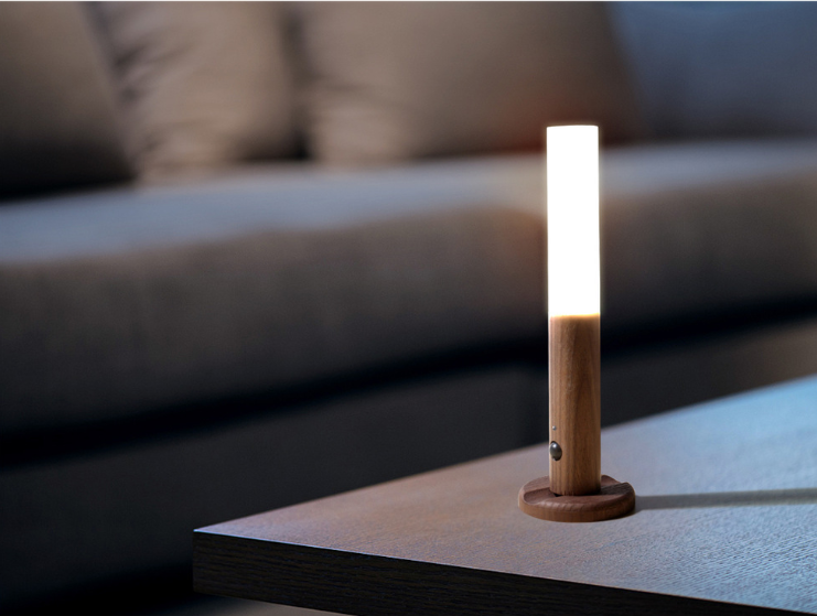 Small wooden lamp on a table with a blurred sofa in the background