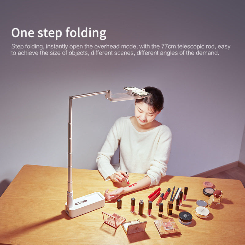Person using a desk lamp with various small objects on a table