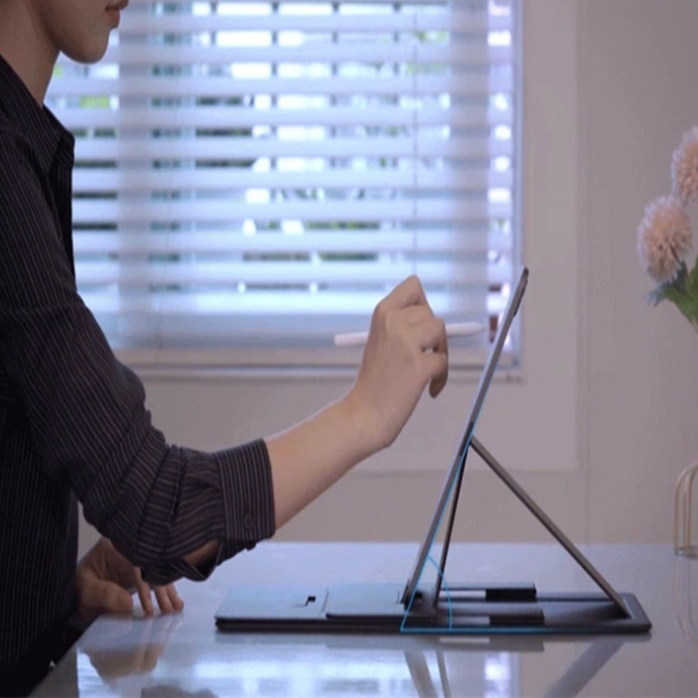 Person using a stylus on a tablet device at a desk with a blurred background