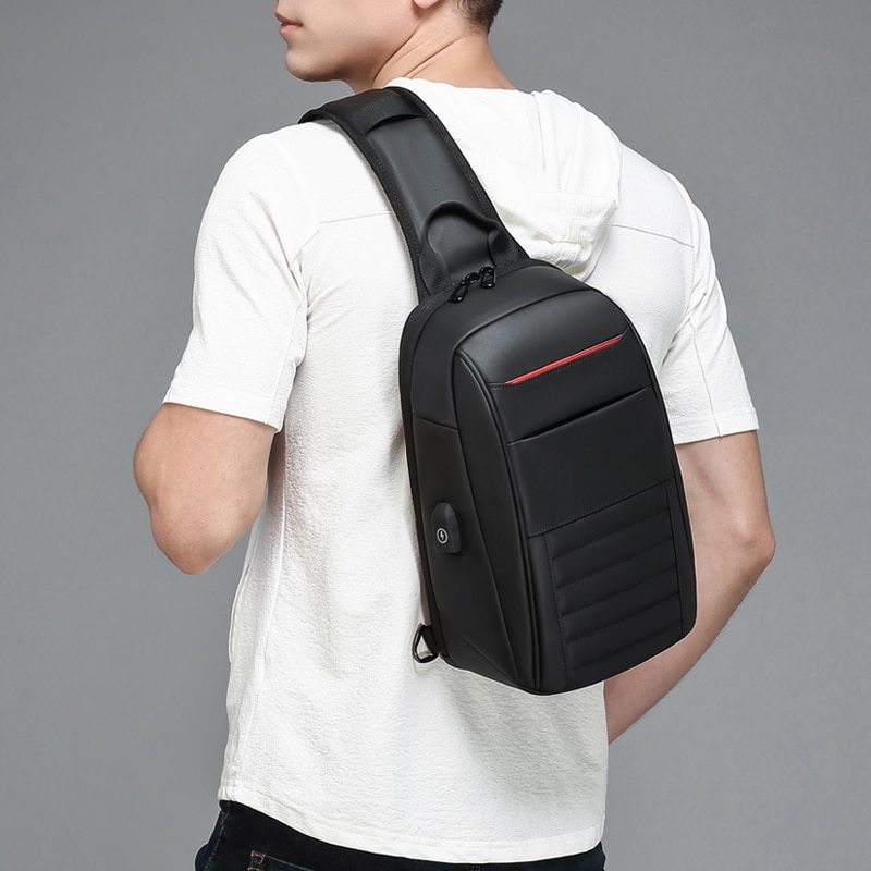 Person wearing a black sling bag with a red accent on a gray background