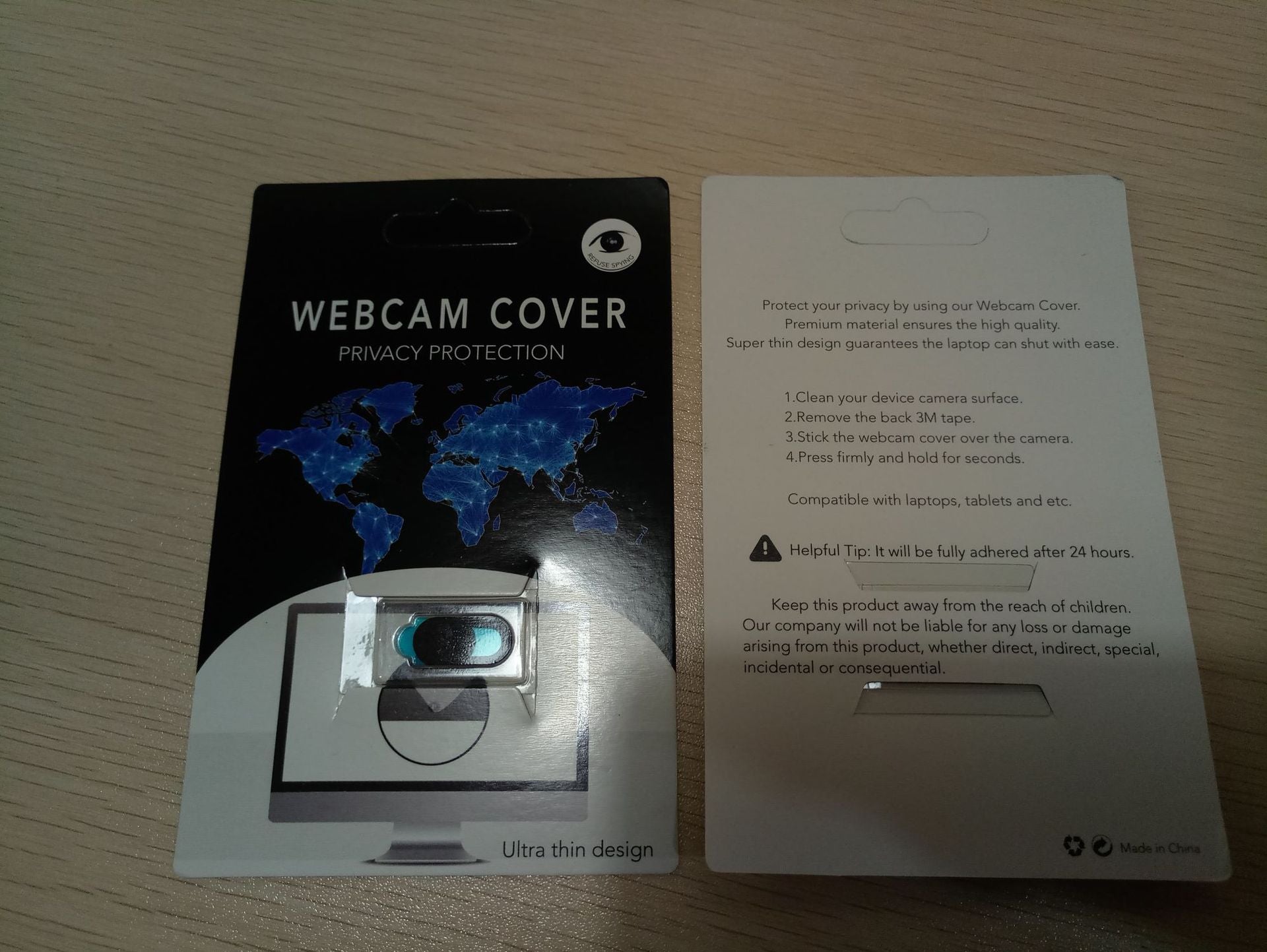 Webcam cover with privacy protection on a card, displayed on a wooden surface.