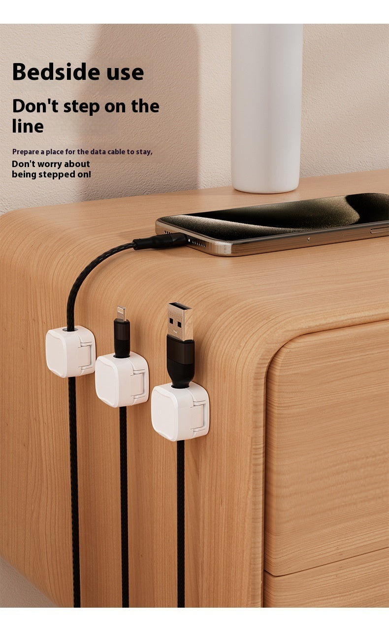 Bedside setup with phone, cable management device, and text on a wooden surface.