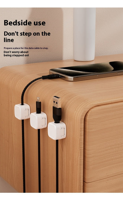 Bedside setup with phone, cable management device, and text on a wooden surface.