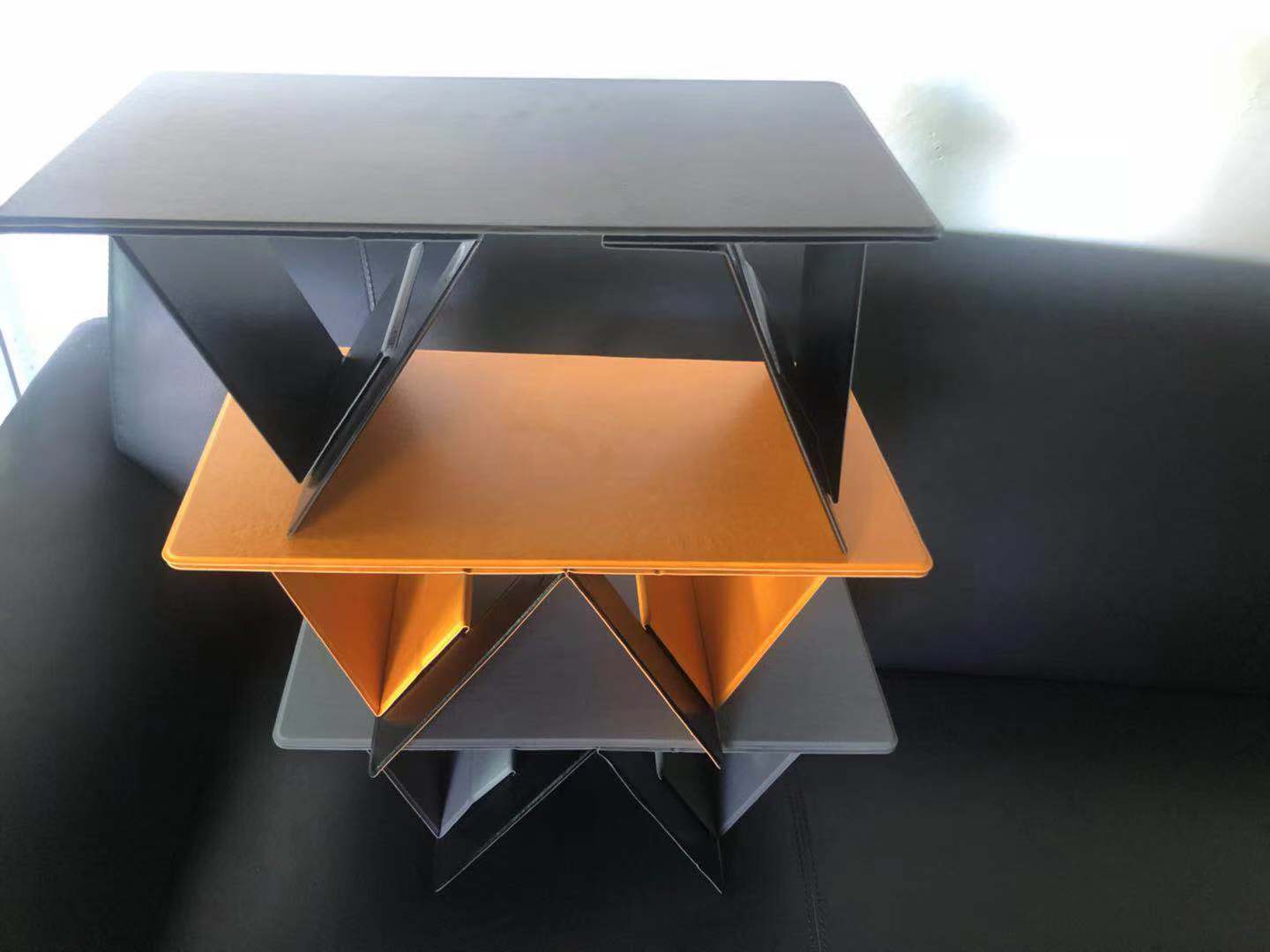 Stack of orange, gray, and black geometric trays on a dark surface.