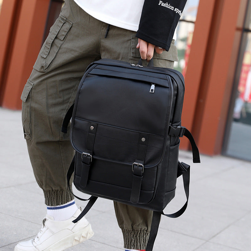Person wearing a black backpack outdoors on a sidewalk.