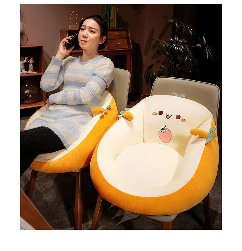 Woman sitting on a chair with a cartoon cushion, surrounded by a cozy indoor setting.