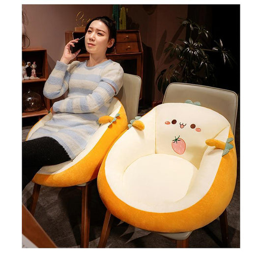 Woman sitting on a chair with a cartoon cushion, surrounded by a cozy indoor setting.