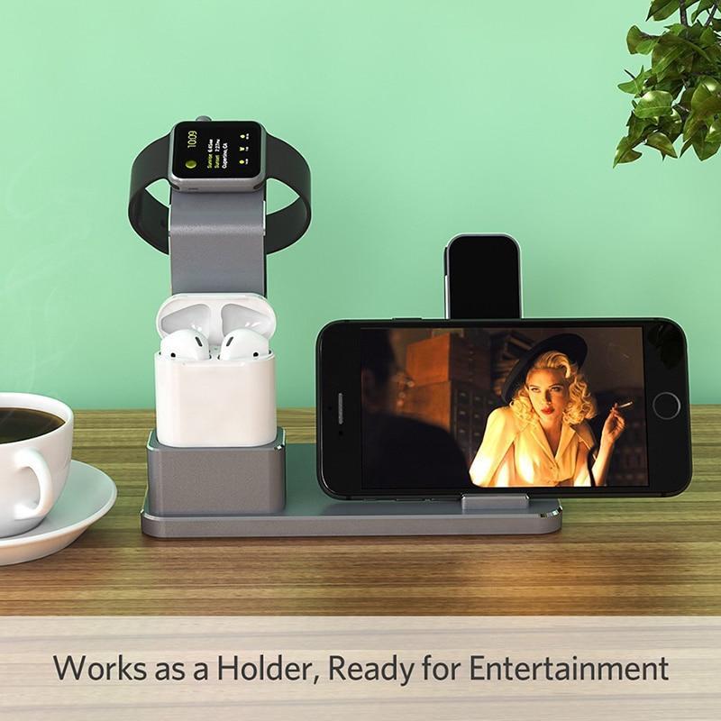 Multi-device charging stand with smartphone, smartwatch, and earbuds on a wooden surface with a green background.