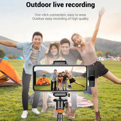 Smartphone with camera on a tripod recording a group of people outdoors with tents and mountains in the background.