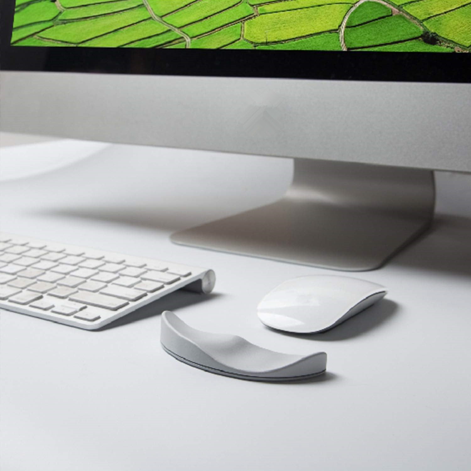 Computer monitor with keyboard, mouse, and wrist rest on a desk
