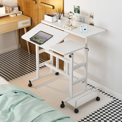 White adjustable desk with a tablet on top, placed next to a bed in a room.