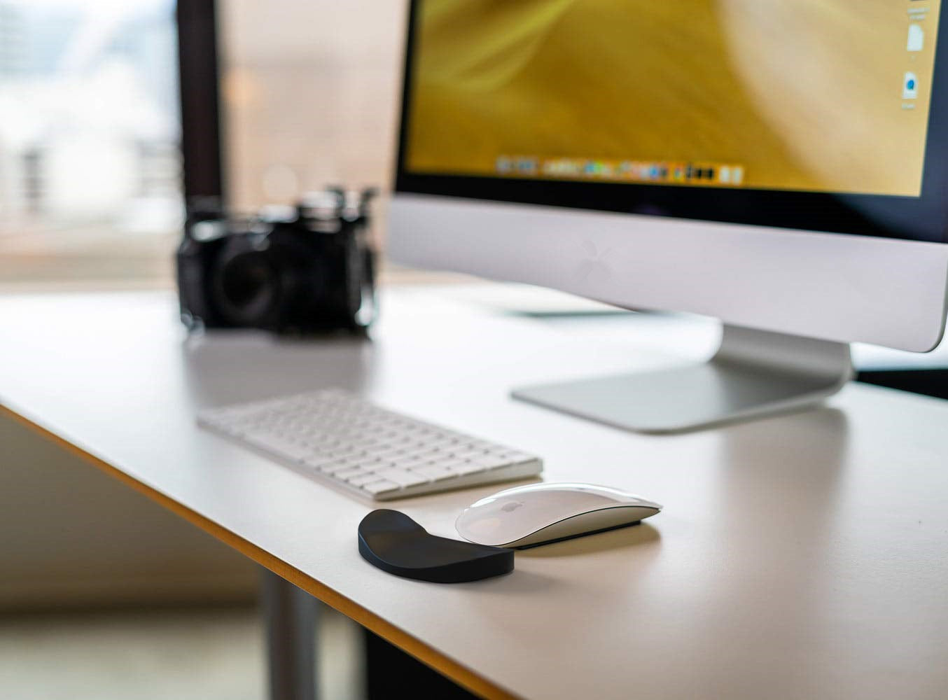 Computer monitor, keyboard, and mouse on a desk with a blurred background