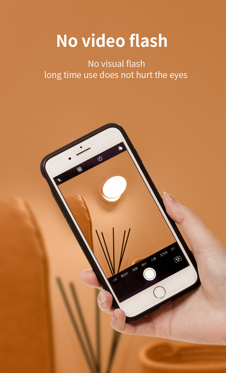 Hand holding a smartphone with a camera app open on an orange background, displaying text about no video flash.