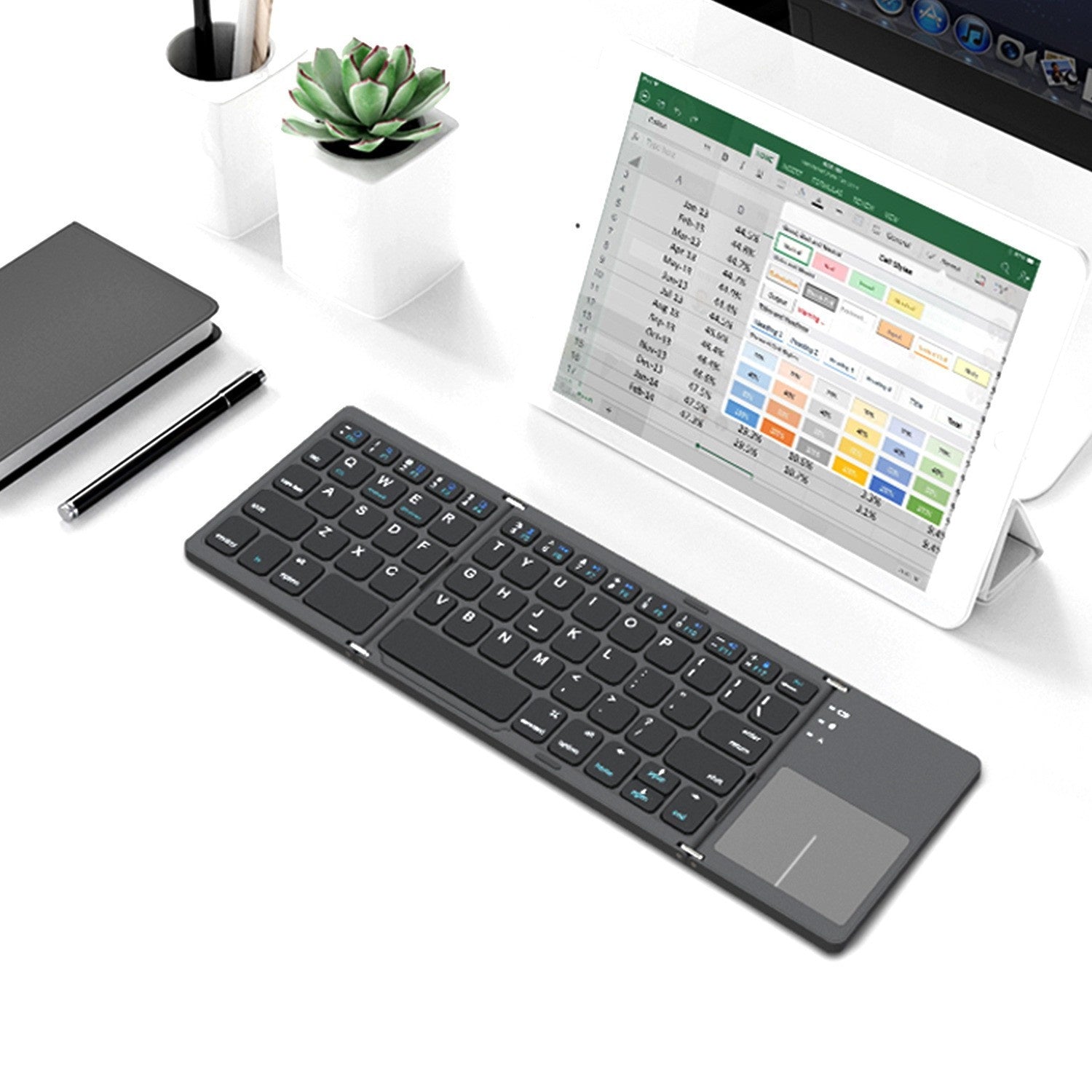 Foldable keyboard on a desk with a tablet displaying a spreadsheet.