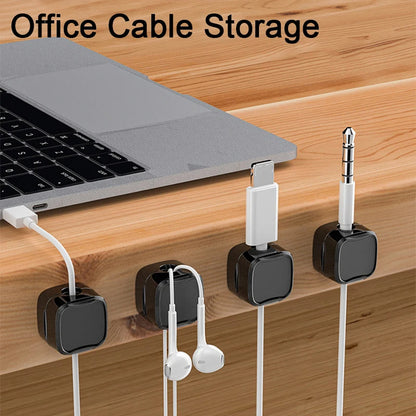 Laptop on a desk with cable organizers holding various cables.